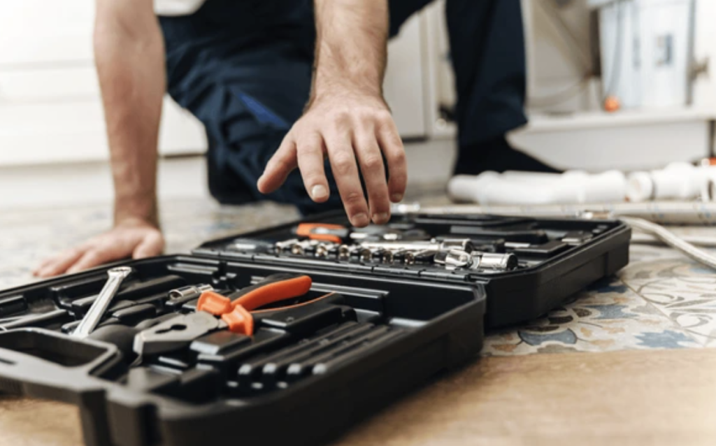 un plombier avec une trousse à outils, en train d’inspecter une installation